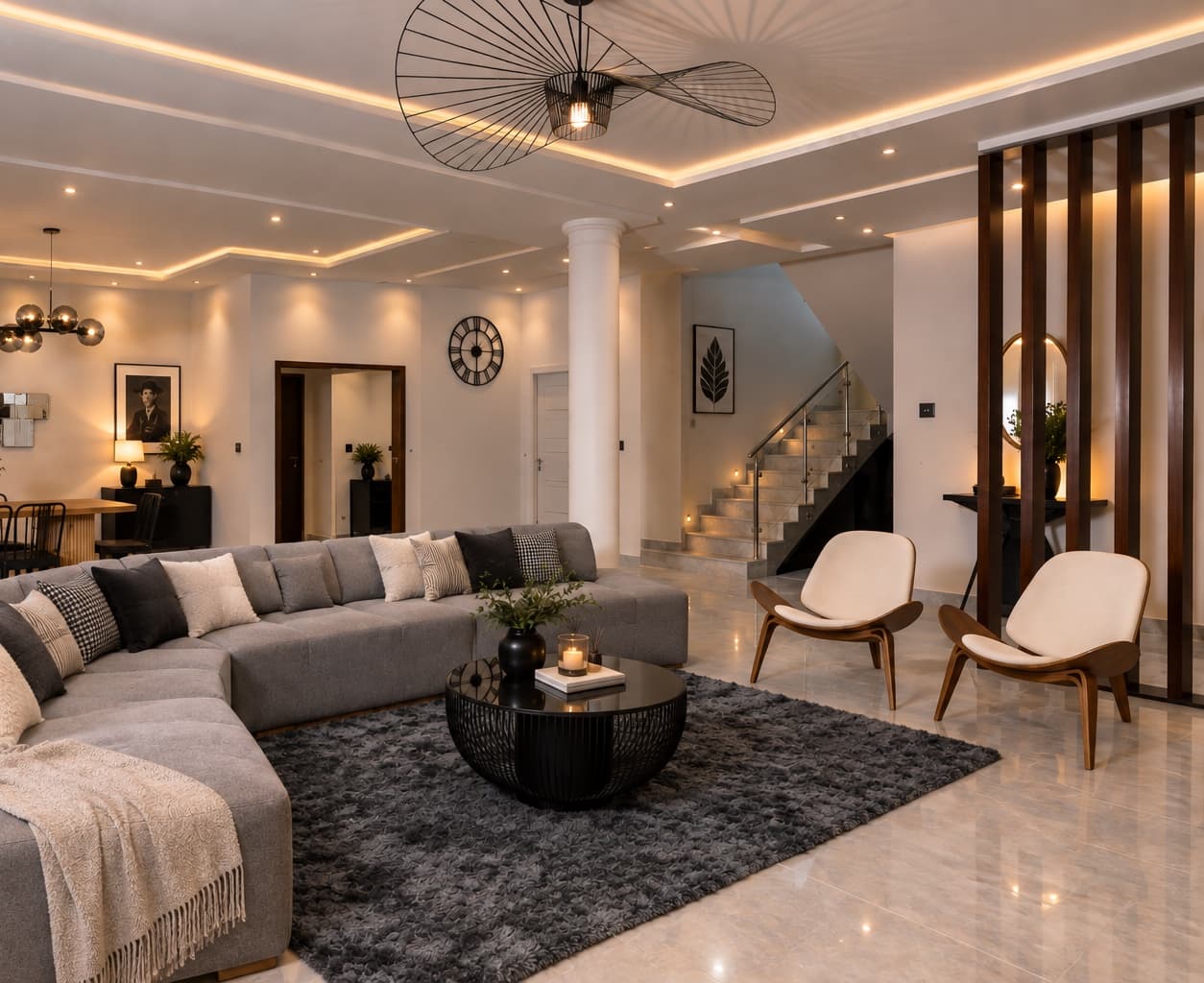 The main lounge at dusk with warm cove lighting, a grey sectional sofa, a black round coffee table and candles